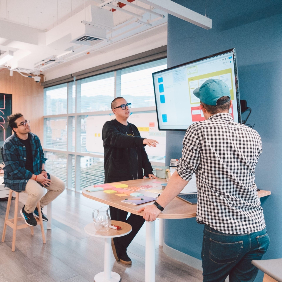 Two men on the work floor talking about something they see on a screen