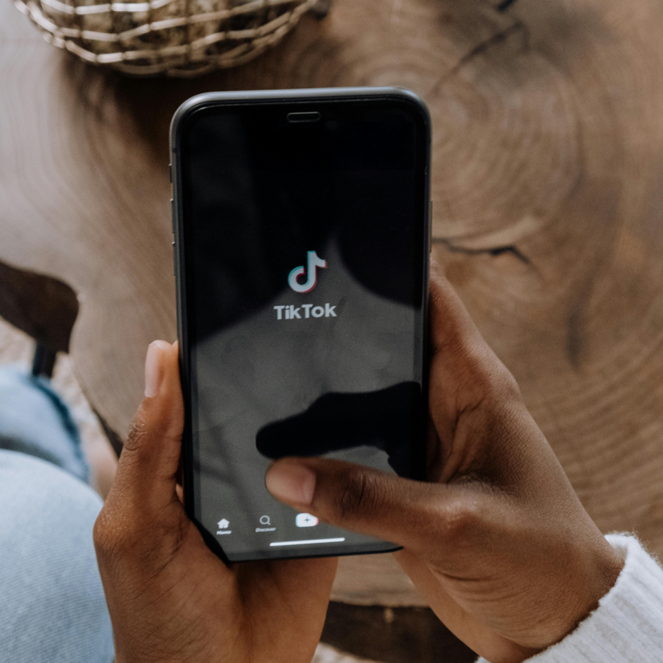 A cellphone showing the tiktok app on it's interface being held by someone