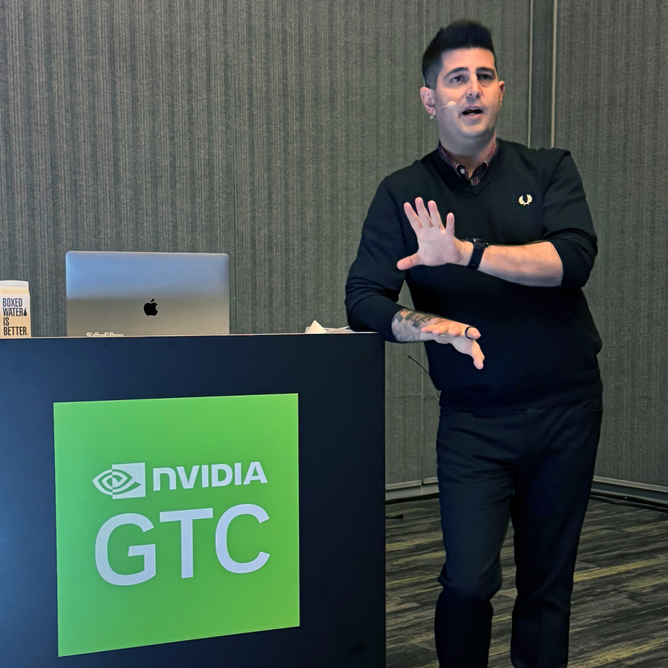 Lewis Smithingham standing at a lectern with a sign that says "GTC 2025" on it