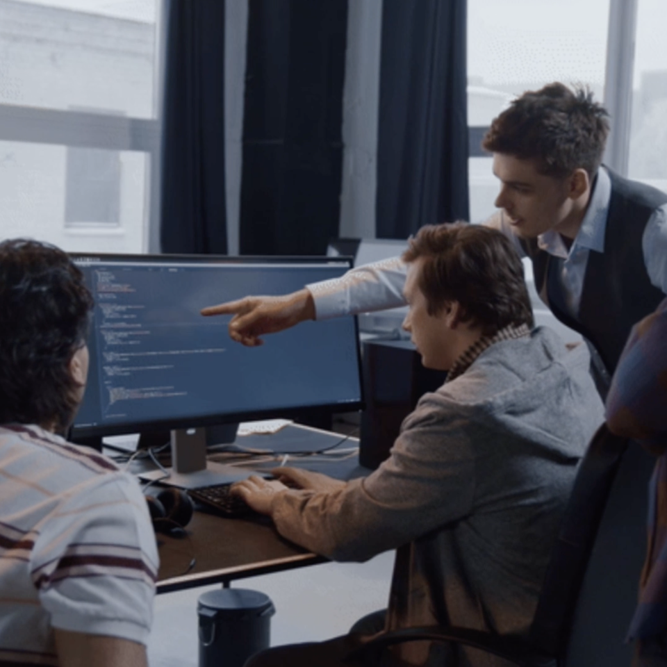 Employees working together around a desk on code