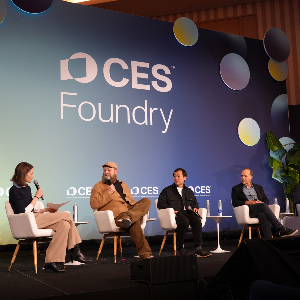 a panel of people on a stage with a sign that reads "CES"