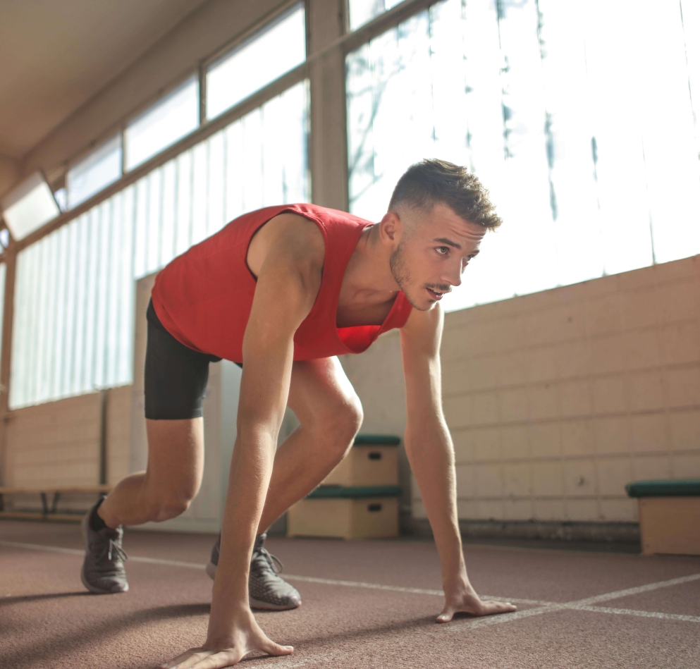 homem em posição de largada para corrida vestindo roupas de atletismo vermelhas