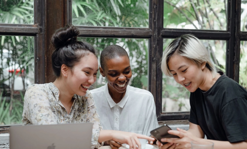 Three employees looking at an iPhone together laughing