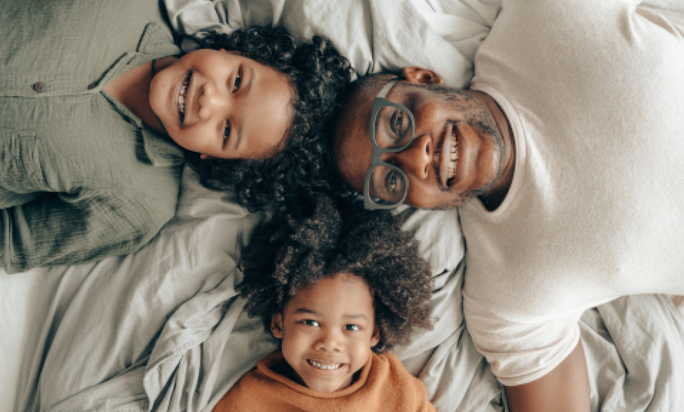 A family lying on a bed smiling