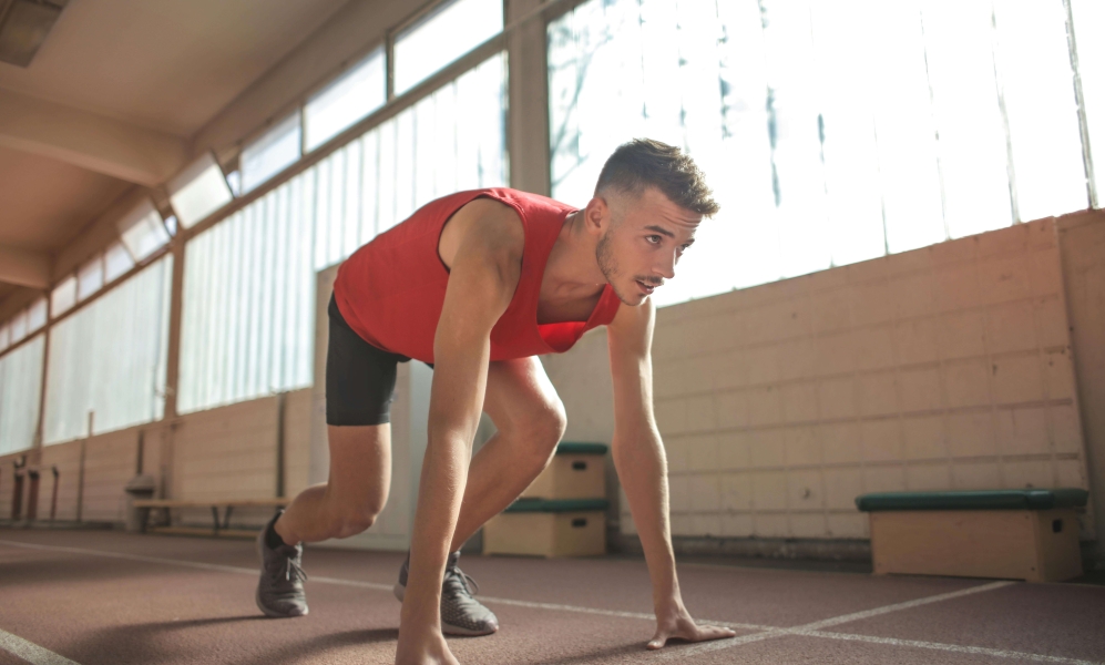 homem em posição de largada para corrida vestindo roupas de atletismo vermelhas