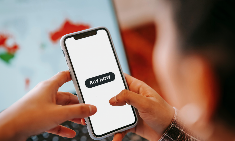 Person looking at their phone at a button saying, "buy now." 