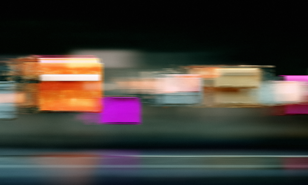 An abstract photograph of colorful rectangular shapes streaked horizontally with motion blur against a dark background.