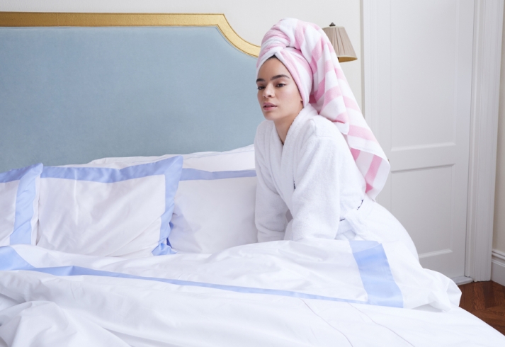 A woman lying on a white bed with a robe and towel