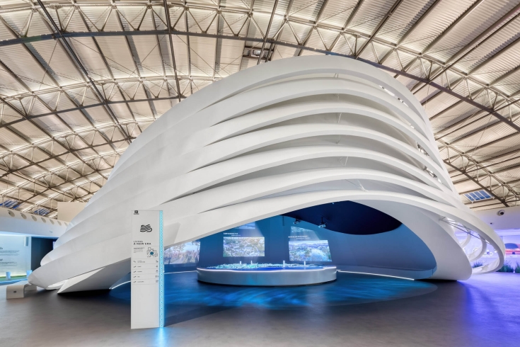 A large white circular exhibit piece with large screens on the inside of it