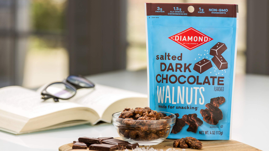 Diamond Foods chocolates in a blue bag on a table with a book and a cutting board