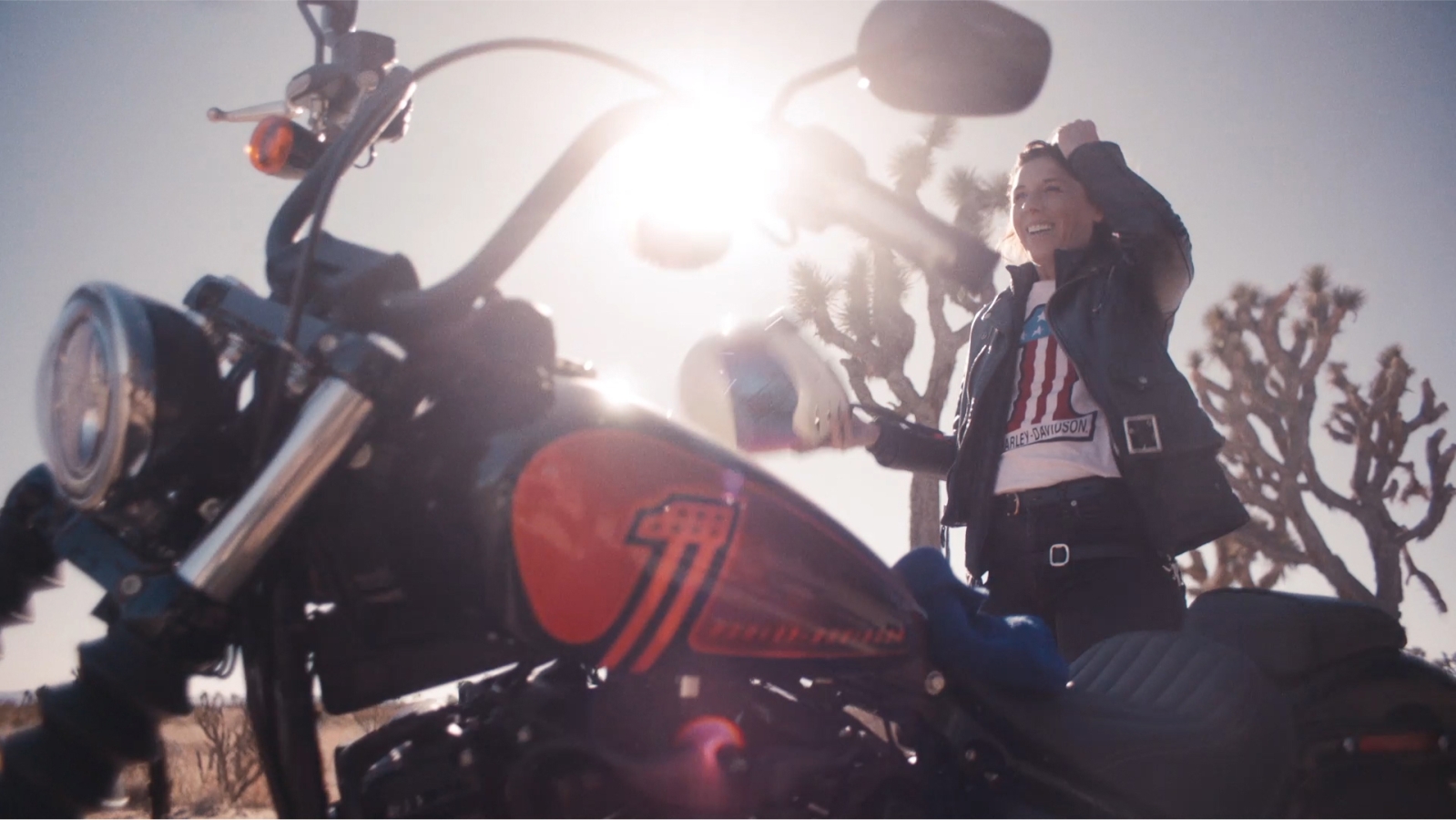 A person standing next to a motorcycle in the sun