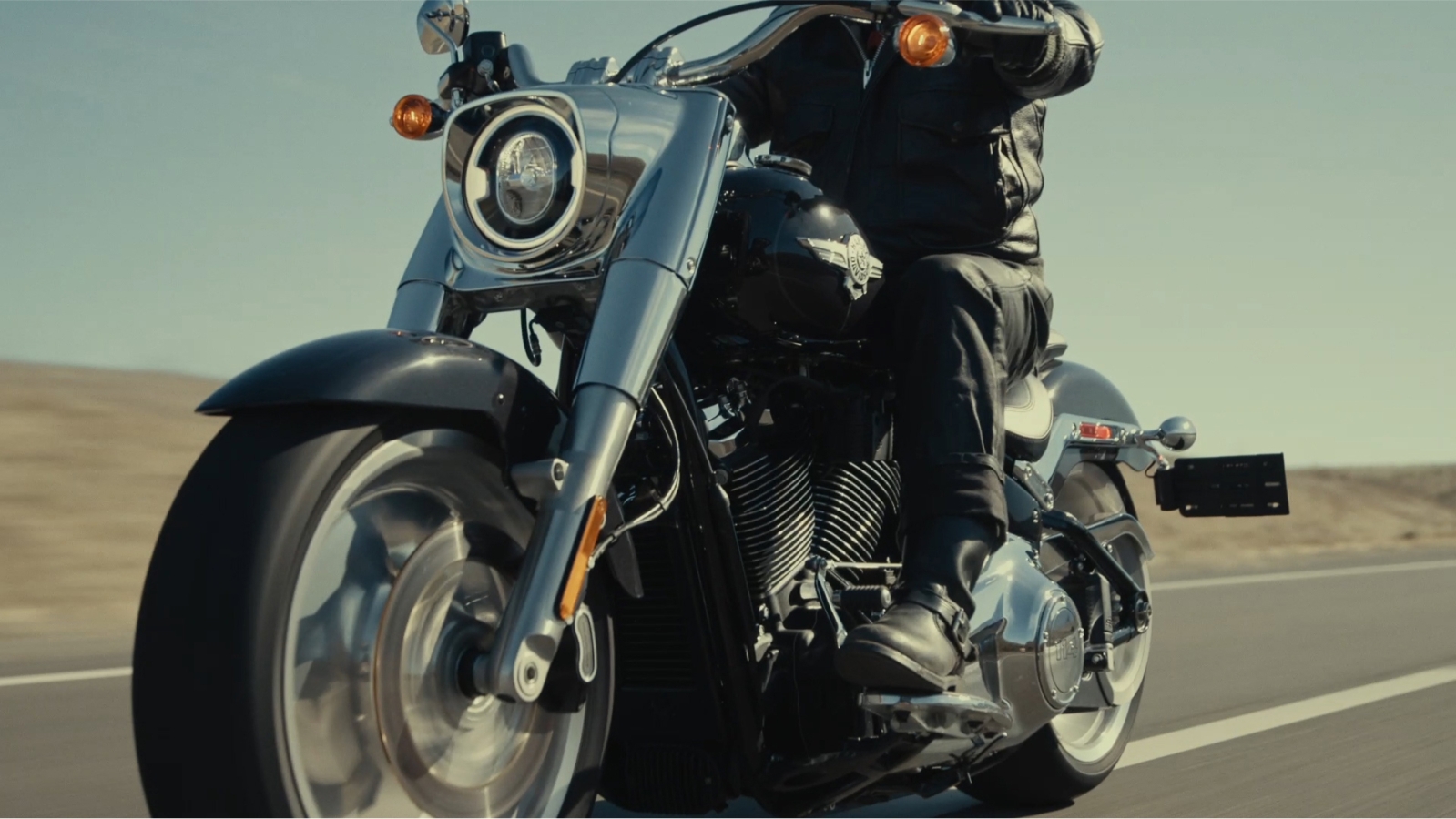 A person riding a motorcycle down a desert road
