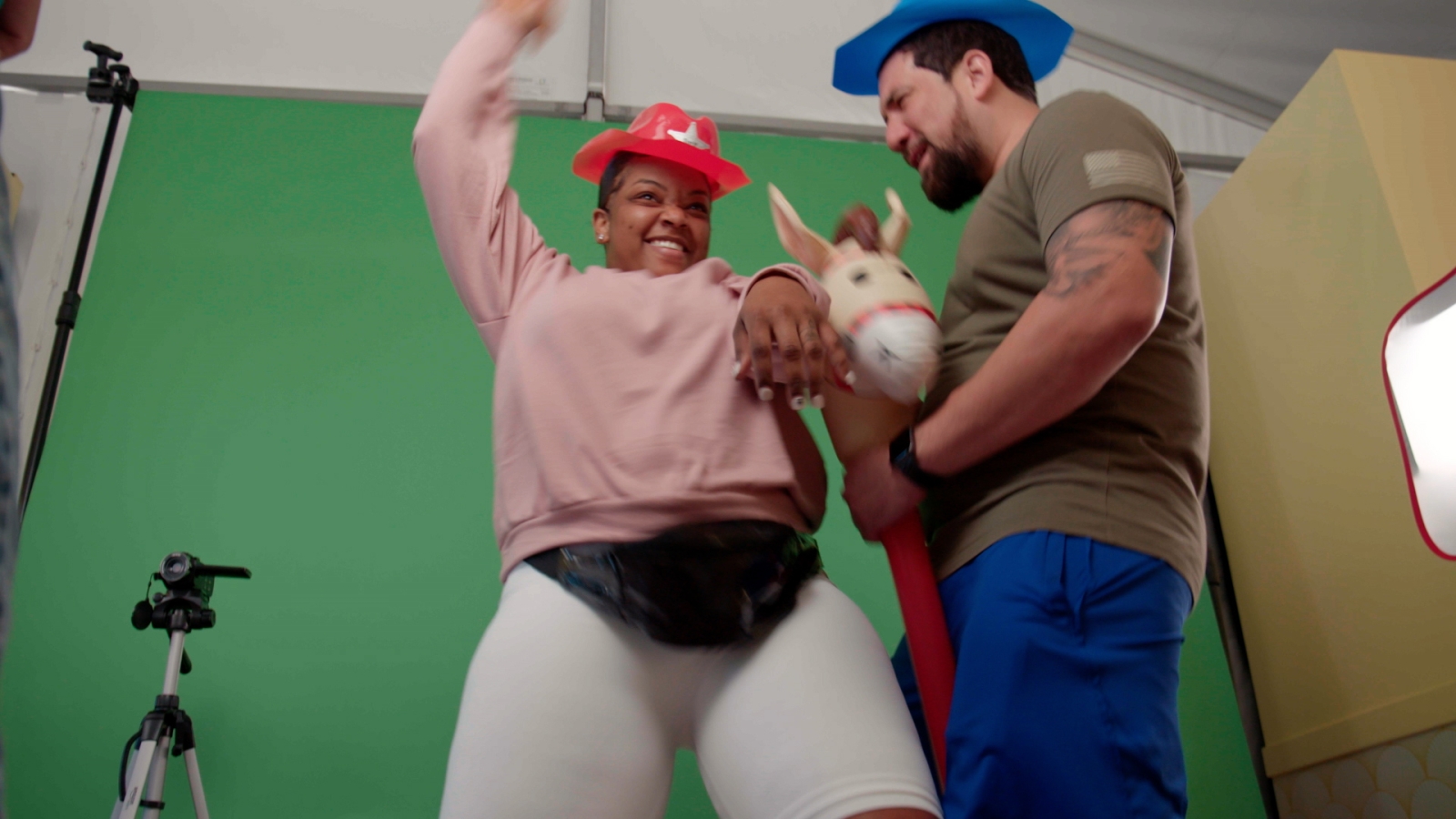 Two people standing in front of a green screen acting out a western scene