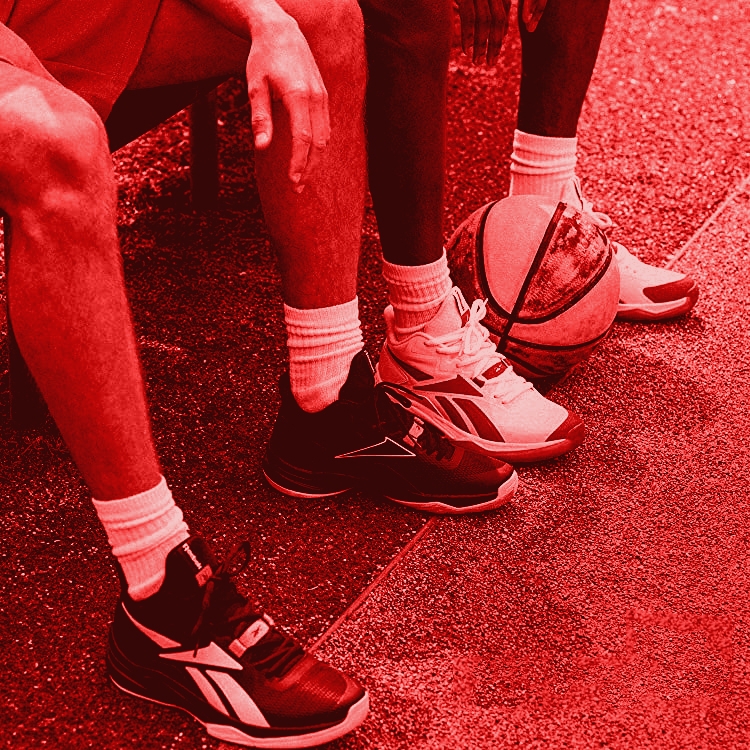 two people sitting on the curb with reebok shoes on