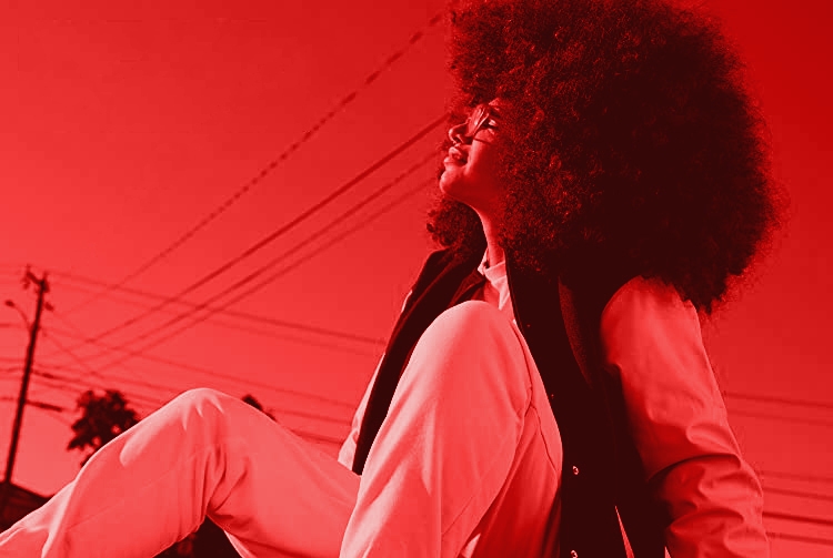A woman sitting on the curb smiling in reebok gear