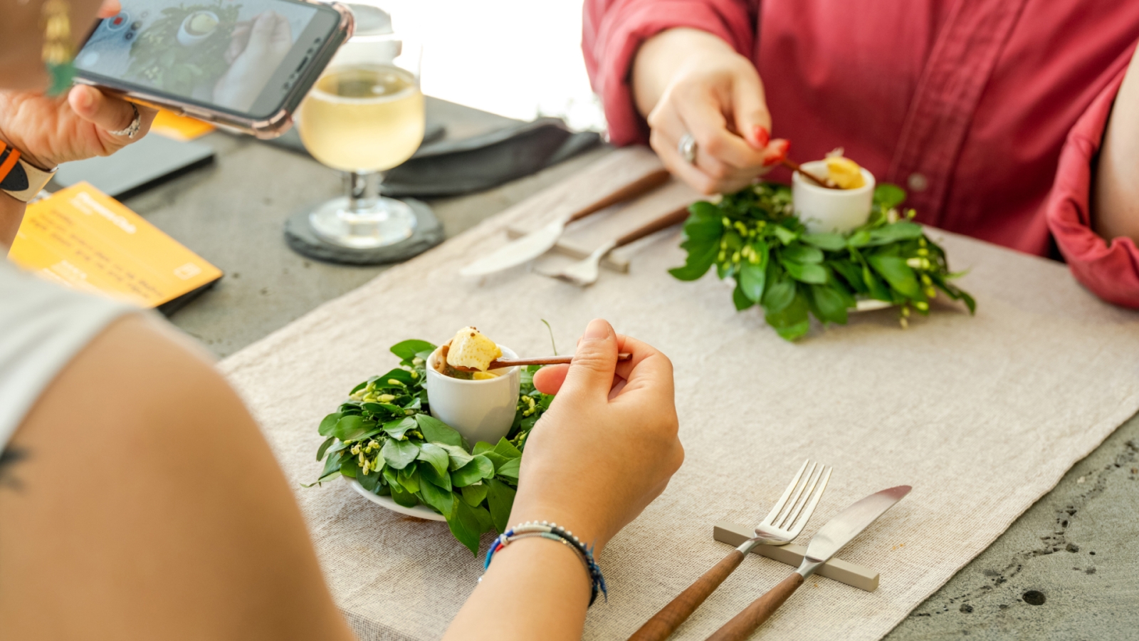 Two people at a table eating a meal and taking a photo of it