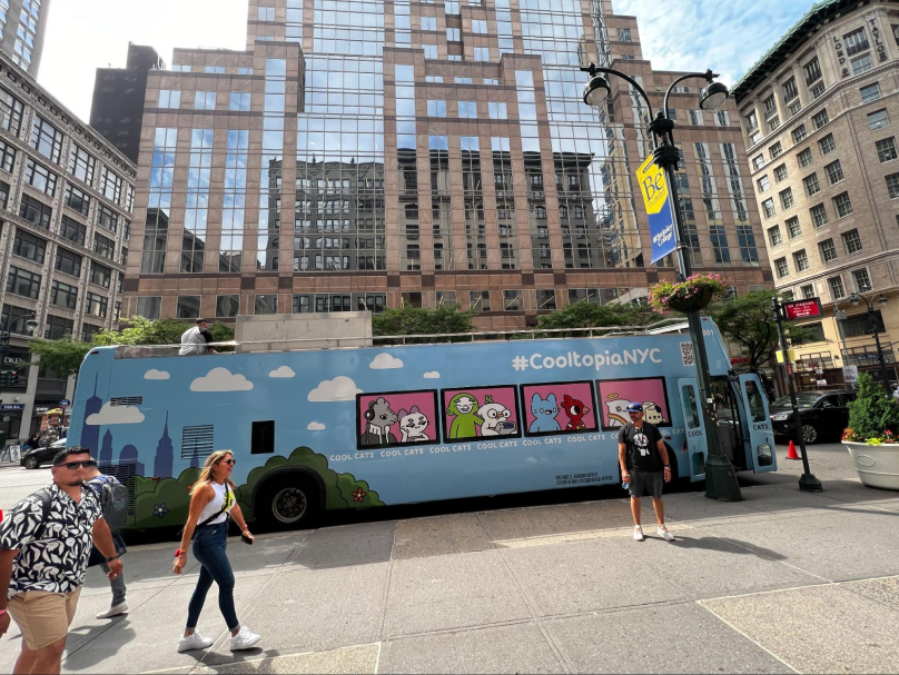 Outside on the street of NYC there's a bus with a large Cooltopia billboard on it