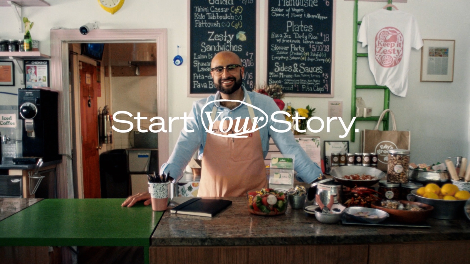 A person stands behind an island in the middle of a kitchen with food sprawled all over it