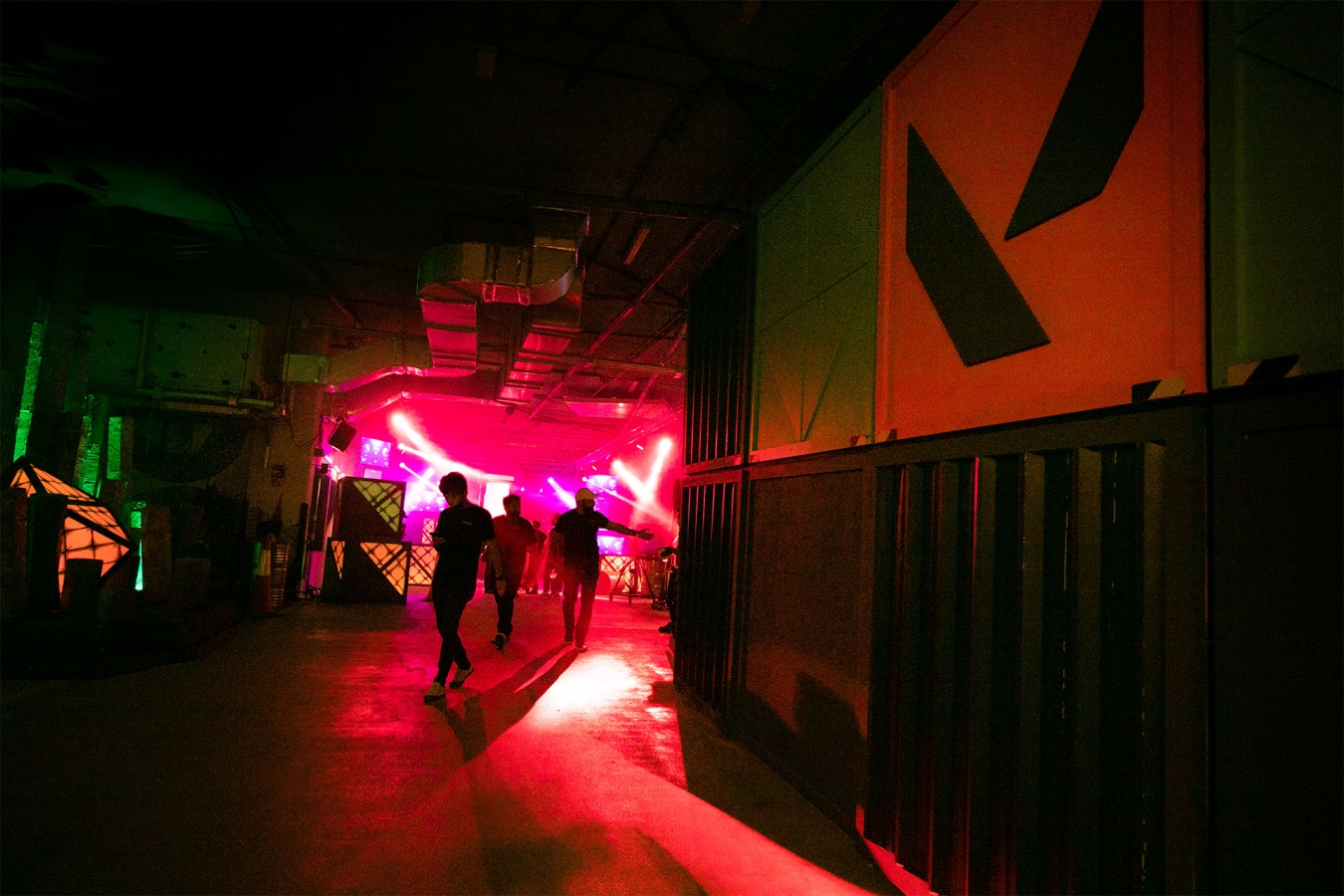 red strobe lights cast shadows of players on the wall in a dark room