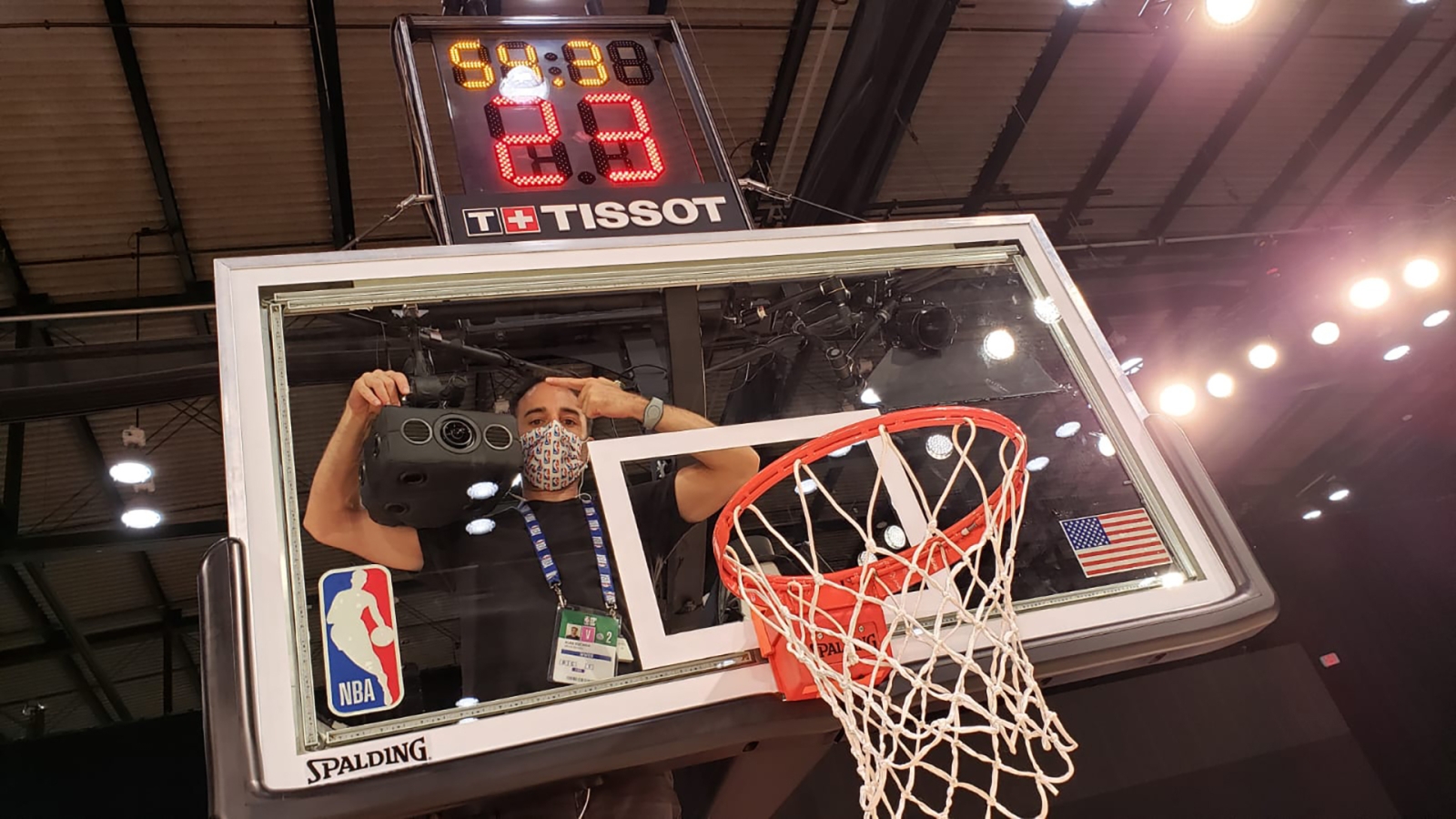 A basketball backboard with a person setting up a camera