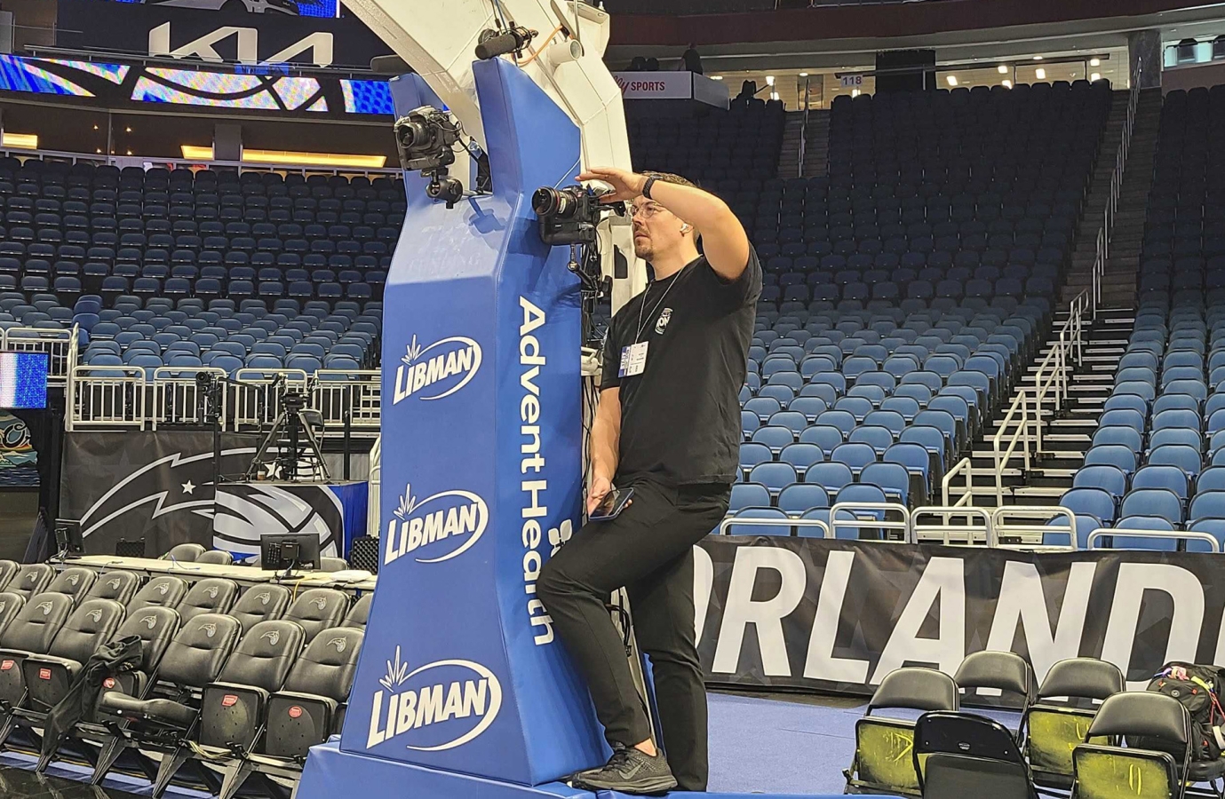 A person setting up a camera attached to a basketball hoop