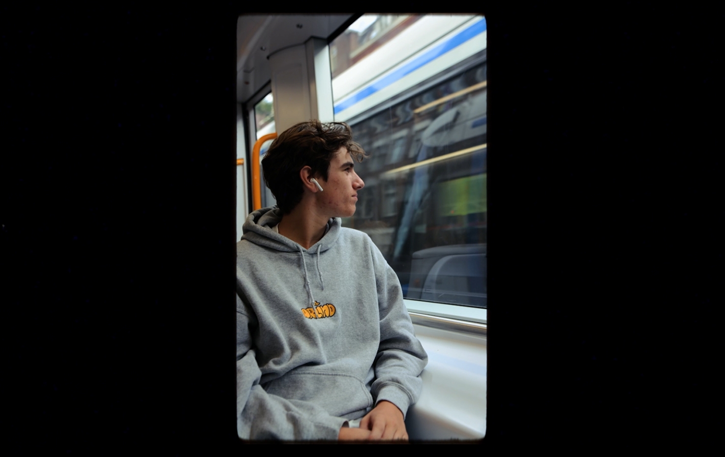 A young male sitting in public transport and staring out of the window.