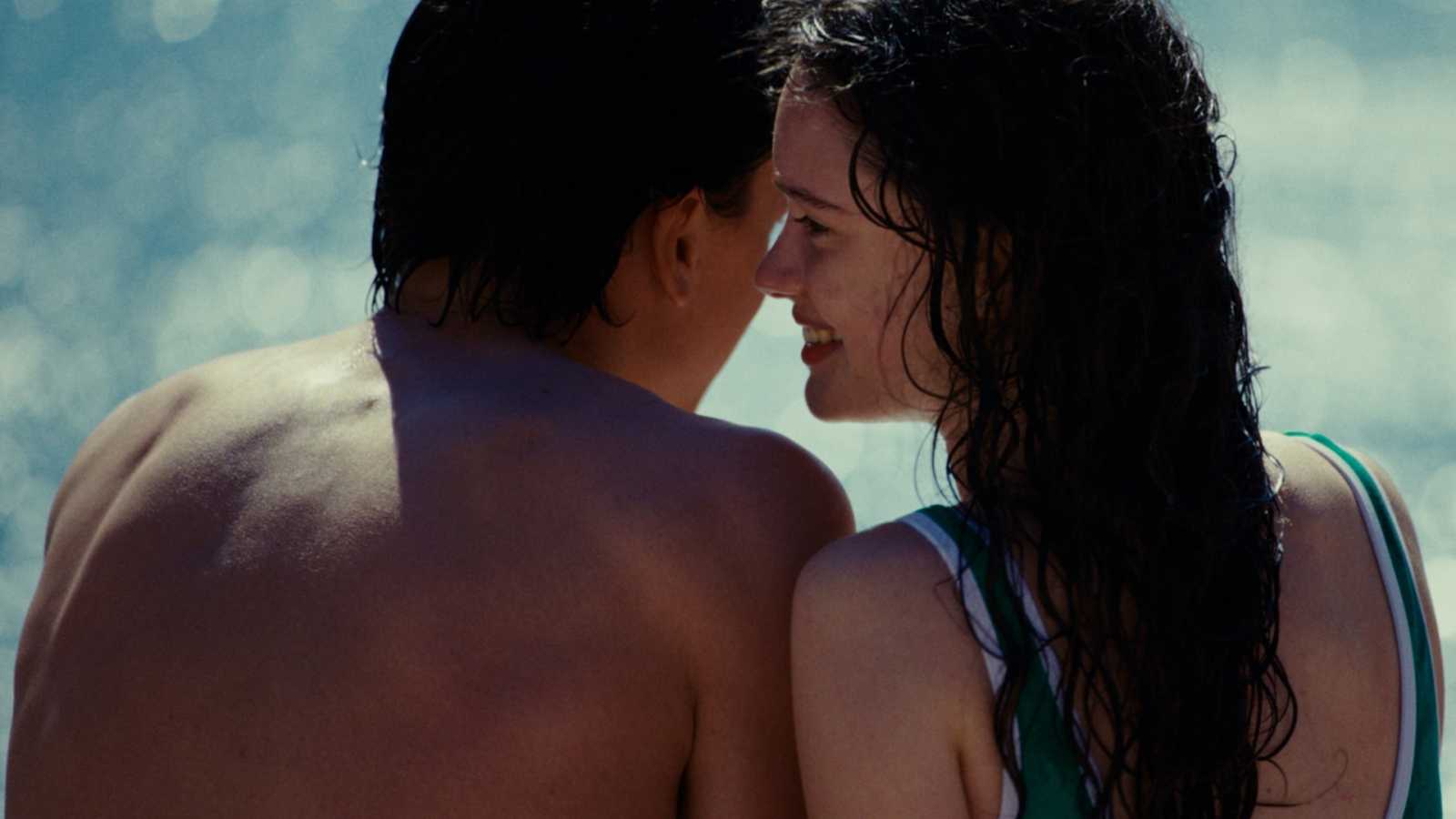 Two people seen from the back in bathing clothes almost kissing each other