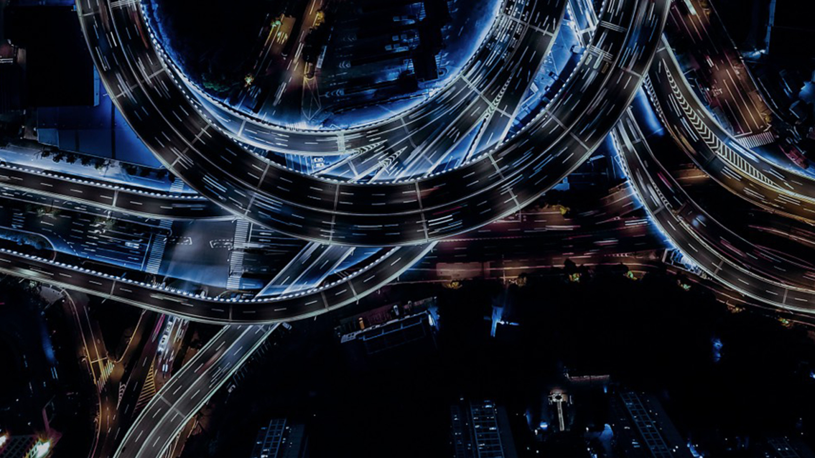 Air shot from above showcasing a highway by night with a circular shape and light purple lights.