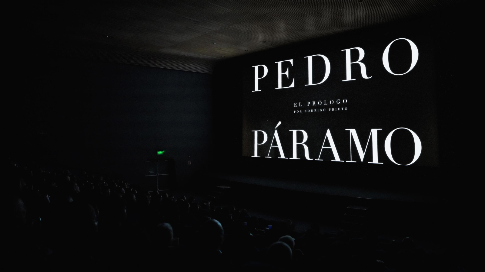 The image portrays a dark theater setting with large, illuminated text showcasing "PEDRO PÁRAMO" and a subtitle "EL PRÓLOGO por RODRIGO PRIETO," while an audience is seated in the foreground.