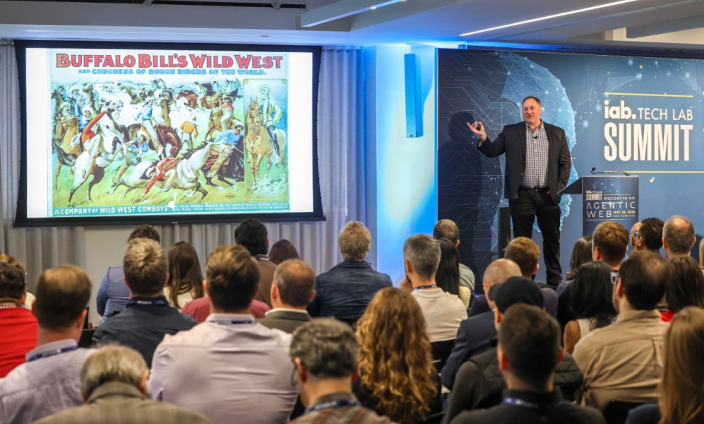 A presenter from the IAB Tech Lab showing a vintage advertisement to a room full of marketing industry leaders.